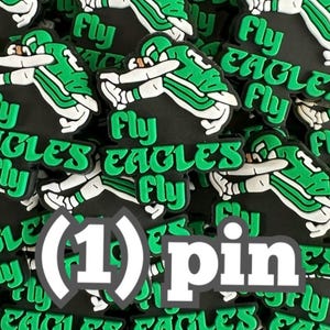 May include: A black and green rubber pin featuring a graphic of a person in a sports uniform performing a dab pose. The text Fly Eagles Fly is embossed in green lettering on the black background. The image includes the white text (1) pin.