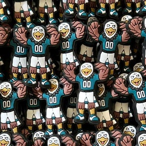 May include: A large group of teal and white plastic charms featuring a cartoon eagle wearing a football jersey with the number "00".