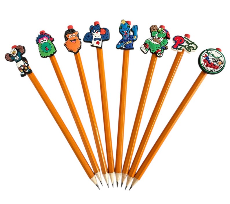 Puede incluir: Un conjunto de ocho l&aacute;pices amarillos, cada uno coronado con una goma de borrar de personajes de dibujos animados. Las gomas presentan varios dise&ntilde;os, incluyendo un jugador de baloncesto, un monstruo verde y un logotipo de equipo de b&eacute;isbol.