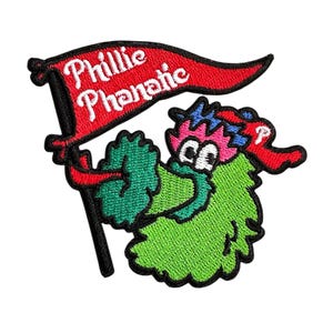 May include: Embroidered patch featuring the Phillie Phanatic, the mascot of the Philadelphia Phillies baseball team. The green, furry creature holds a red banner with the words "Phillie Phanatic" in white. The patch has a black border.