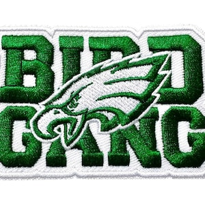 May include: Embroidered patch with the words "BIRD GANG" in green block letters. A white and green eagle head graphic is in the center. The patch has a white border.