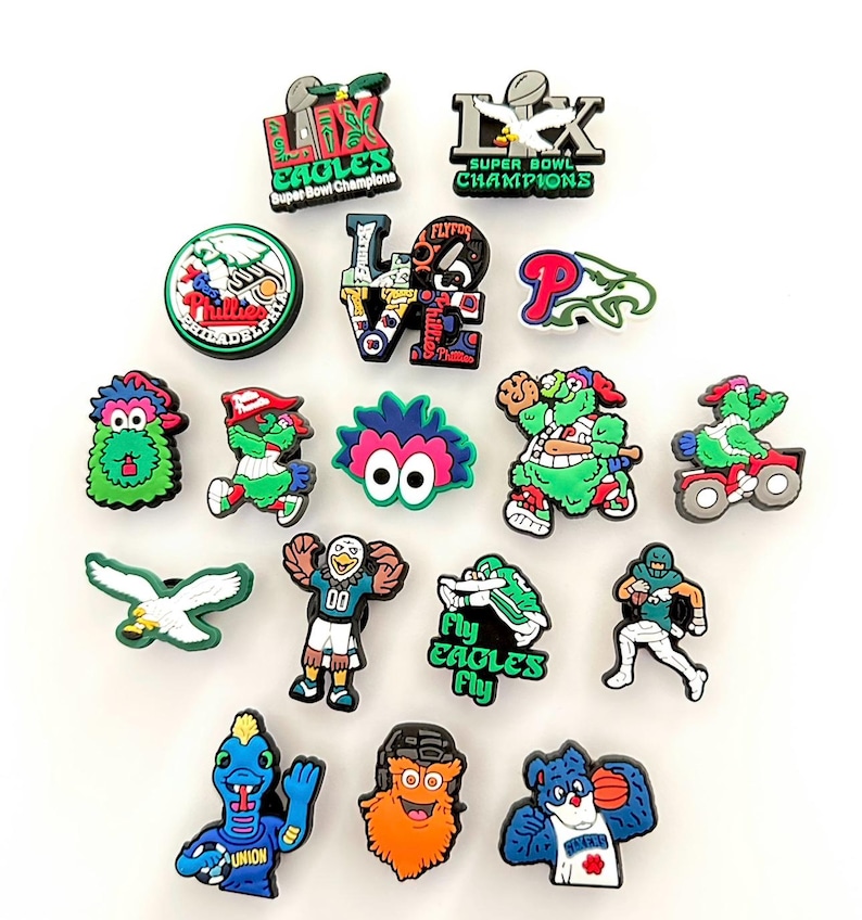 May include: A collection of 17 colorful shoe charms featuring the Philadelphia Eagles logo, mascot, and other team-related imagery. The charms include the words "Fly Eagles Fly", "Super Bowl Champions", and "Love".