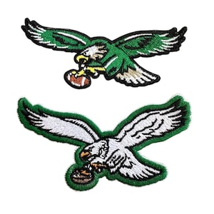 May include: Two embroidered patches featuring eagles in flight, holding footballs. One patch is green and white, the other is white and green. Both patches have a green border and are on a white background.