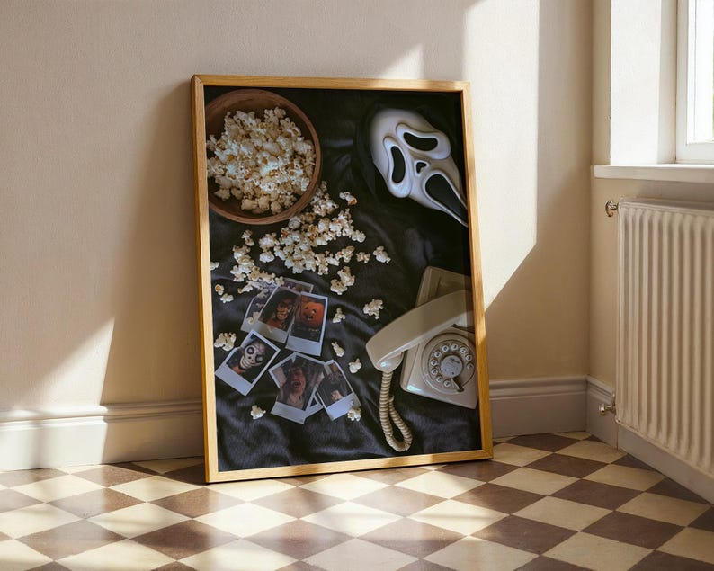 May include: A framed image with a horror movie theme. It features a Scream mask, popcorn in a wooden bowl, a vintage telephone, and Polaroid photos with horror movie images. The background is black.