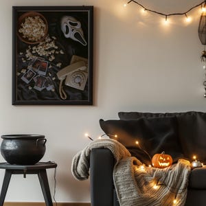May include: A Halloween-themed living room. A framed picture features a Scream mask, popcorn, and a vintage telephone. A carved pumpkin sits on a blanket over a black sofa, lit by fairy lights. A black cauldron sits on a small table.