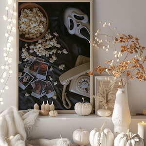 May include: A Halloween display with a framed image of a Scream mask, popcorn, and a vintage phone. White pumpkins, candles, and a vase with dried flowers create a spooky atmosphere. A string of fairy lights provides a soft illumination.