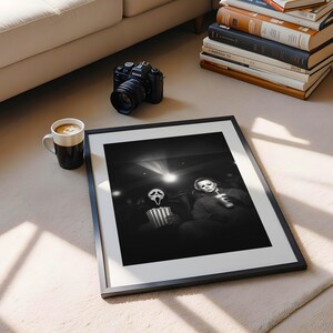 May include: A framed black and white photograph featuring two horror movie characters in a movie theater setting. A black camera, a coffee mug, and a stack of books are also visible.