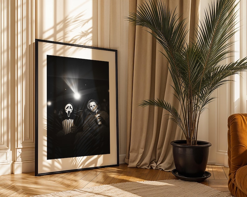 May include: Black and white framed print featuring two horror movie characters in a movie theater setting. One character wears a Scream mask and holds popcorn, the other holds a drink. A spotlight shines on them.