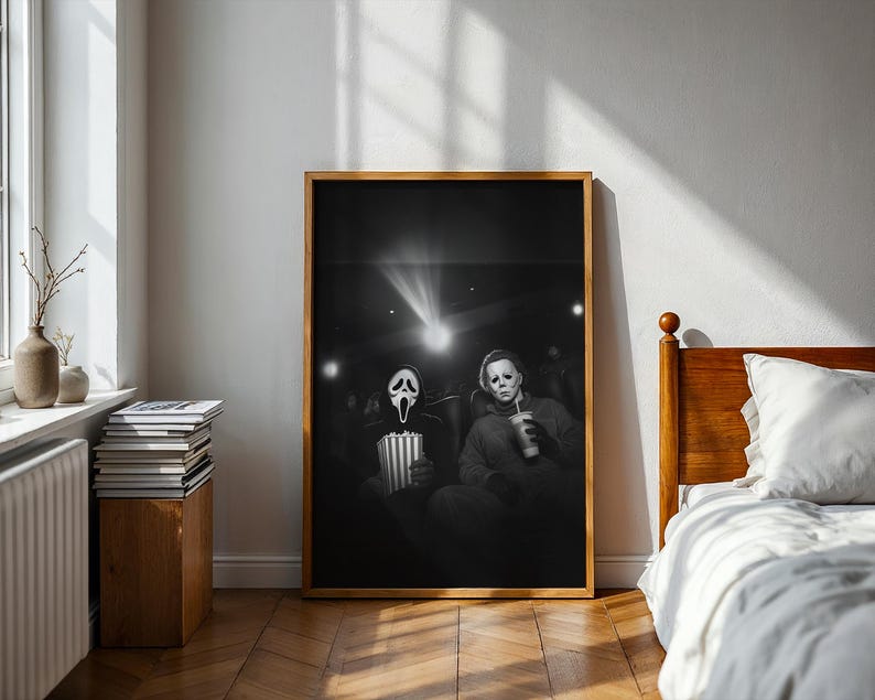 May include: Black and white framed print featuring two iconic horror movie characters in a movie theater setting. One holds popcorn, the other a drink. The image is illuminated by the projector's light.