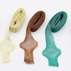 Könnte beinhalten: Eine Auswahl an dekorativen Bändern in Beige, Gelb, Braun, Türkis und Grün. Jedes Band hat ein einzigartiges, offen gewebtes Design und ein dekoratives, ausgestelltes Ende. Die Bänder sind auf einer weißen Oberfläche angeordnet.