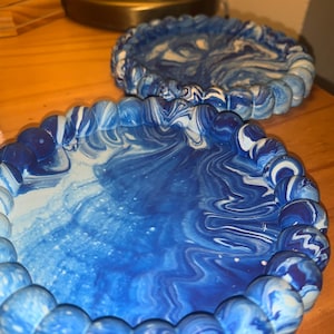 May include: Two blue and white swirl patterned coasters with a raised beaded edge.