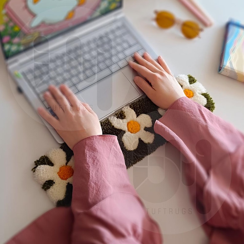 May include: A person using a laptop computer on a green and white floral rug with the text "LUFT RUGS".