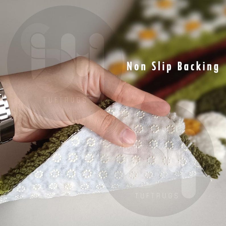 May include: Close-up of a rug with a white, non-slip backing. The rug has a green border and a floral design with white and yellow flowers. The text "Non Slip Backing" is visible.