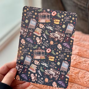 May include: A dark blue patterned tablet cover featuring illustrations of a gazebo, coffee cups, a dog, a jeep, and text that reads "Luke's", "Where you lead I will follow", and "I smell snow".