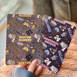 May include: Two square coasters with hockey-themed designs. One coaster features a gray background with hockey equipment and the text "Boston Raiders" and "Rozanov 81". The other has a black background with "Montreal Metros" and "Hollander 24".