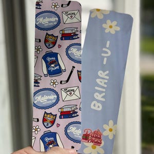 May include: Two rectangular bookmarks. One is light purple with a pattern of hockey jackets, books, and the text "Malone's Hastings, MA" and "Briar Hockey". The other is light blue with white daisies and the text "BRIAR -U-" and "Pixels Pages".