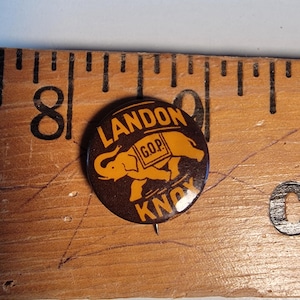 May include: A brown and orange political campaign button featuring an elephant with the text "LANDON GOP KNOX" on it.