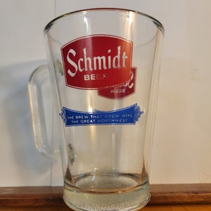 May include: A glass beer mug with a red and blue logo that says "Schmidt Beer" and "The Brew That Grew With The Great Northwest".