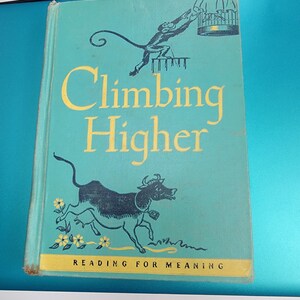 May include: Vintage book titled "Climbing Higher" with a teal cover. The cover features illustrations of a monkey reaching for a cage and a running bull. The title is in yellow, and the text "Reading for Meaning" is at the bottom.