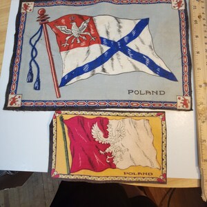 May include: Two vintage fabric patches with the Polish flag and the word "POLAND" printed on them. The top patch features a white flag with a blue cross and a red eagle. The bottom patch features a white and red flag with a white eagle.