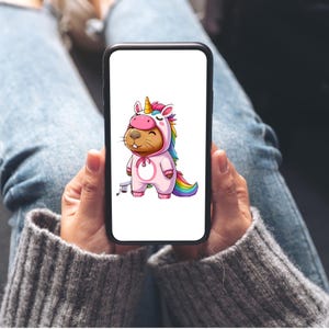 以下が含まれることがあります： スマートフォンには、ピンク色のユニコーンのコスチュームを着たビーバーの漫画イラストが表示されています。虹色のたてがみと尻尾があります。ビーバーは笑顔です。背景は白です。