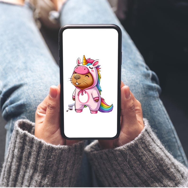 以下が含まれることがあります： スマートフォンには、ピンク色のユニコーンのコスチュームを着たビーバーの漫画イラストが表示されています。虹色のたてがみと尻尾があります。ビーバーは笑顔です。背景は白です。