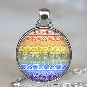 May include: A silver-toned pendant necklace with a round, glass-covered charm. The charm features a colorful, striped design with floral and geometric patterns in shades of red, orange, yellow, green, blue, and purple. The necklace has a silver chain.