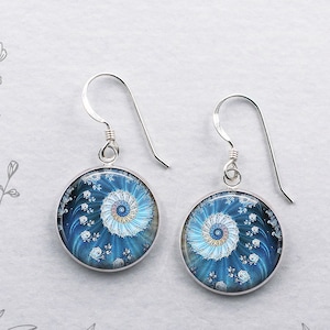 May include: A pair of silver-toned drop earrings. Each earring features a round, blue and white design with a spiral pattern. The earrings have a hook closure. The design is reminiscent of a nautilus shell.