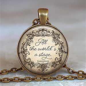 May include: A round, antique gold-toned pendant necklace. The pendant features the quote "All the world's a stage" by Shakespeare, surrounded by an ornate floral design. The chain is also gold-toned.