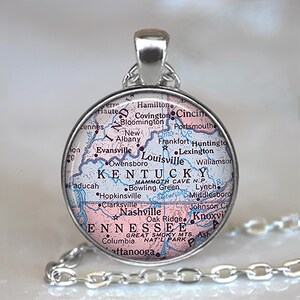 May include: A silver-toned pendant necklace featuring a circular pendant with a map design. The map highlights Kentucky and Tennessee, with cities like Louisville and Nashville visible. The pendant hangs from a silver chain.