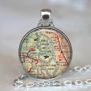 May include: A round silver pendant featuring a map of Sequoia National Park. The map includes roads, geographical features, and the text "Sequoia National Park." The pendant hangs from a silver chain.