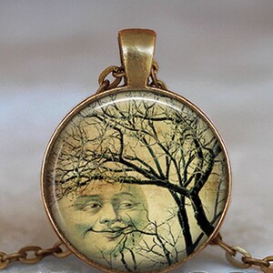 May include: A round pendant necklace featuring a bronze-toned metal frame and a glass cabochon. The image inside depicts a vintage-style illustration of a smiling moon face partially obscured by the dark, intricate branches of a bare tree.