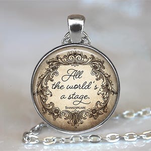 May include: Silver-toned pendant necklace featuring a round charm with the quote "All the world's a stage" in elegant script. The quote is framed by ornate floral and scrollwork designs, with the name "Shakespeare" below. The chain is a delicate silver link.