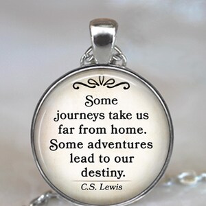 May include: Silver-toned pendant necklace with a round charm. The charm features the quote "Some journeys take us far from home. Some adventures lead to our destiny." by C.S. Lewis, in black text on a cream background.