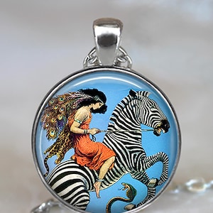 May include: A silver pendant necklace with a round glass cabochon featuring a vintage illustration of a woman riding a zebra. The woman is wearing a red dress and a peacock feather headdress. The zebra is black and white with a snake wrapped around its legs.