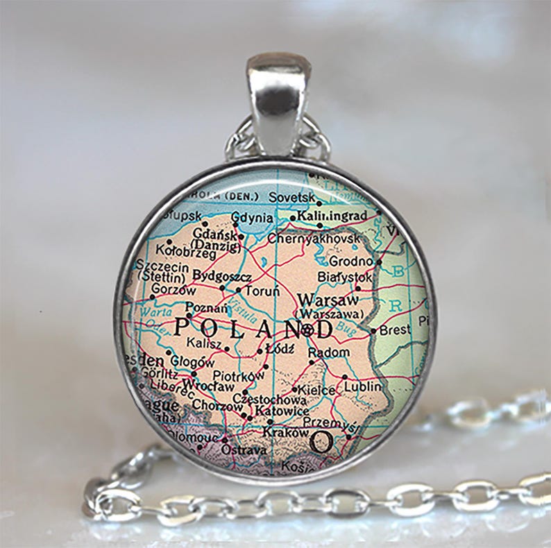May include: A silver-toned pendant necklace featuring a circular charm with a map of Poland. The map displays cities like Warsaw, Krakow, and Gdansk, with a silver chain attached.