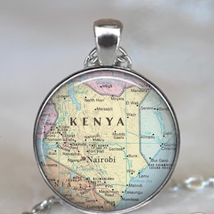 May include: A silver necklace with a round glass pendant featuring a map of Kenya. The map shows major cities and geographical features, including Nairobi, Mount Kenya, and Lake Turkana.