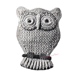 Puede incluir: Un búho de crochet con ojos negros y una banda negra alrededor del cuello. El búho está hecho con hilo gris y blanco.