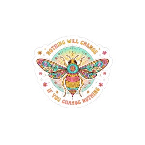 May include: A vibrant sticker with a detailed bee design, showcasing wings in pink, blue, yellow, and green. The bee has a turquoise body, and the sticker includes the text "Nothing Will Change If You Change Nothing" and small floral motifs.