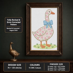 May include: A cross-stitch pattern of a white goose with pink flowers, an orange beak and feet, and a blue bow, framed in dark wood. Text reads: Fully Revised & Error-Corrected Pattern, Revised & Corrected – August 2026. Includes size and color info.
