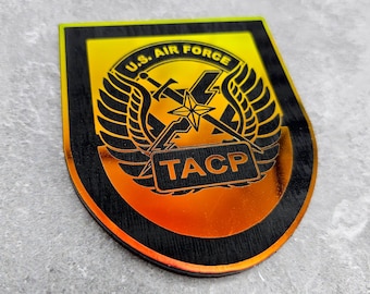 Op de afbeelding: Een zwart en gele patch met de tekst "U.S. AIR FORCE" en "TACP" in een zwart rechthoek. De patch heeft een gestileerde afbeelding van gekruiste zwaarden en vleugels.