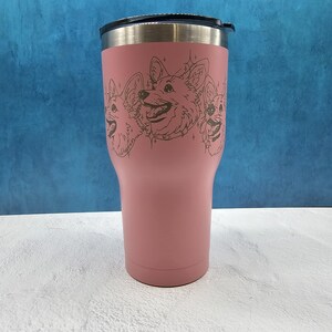May include: A pink stainless steel tumbler with a black lid and a design of three corgi dogs in a line. The dogs are outlined in black and have a white background.