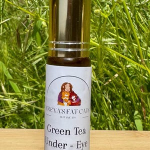 Peut inclure: Un flacon de roll-on dor&eacute; et blanc avec une &eacute;tiquette qui indique "FREYA'S FAT CATS BOTANICALS" et "Green Tea Under-Eye Serum".