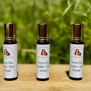 Peut inclure: Trois flacons roulants en verre dor&eacute;s et bruns avec des &eacute;tiquettes blanches. Les &eacute;tiquettes portent le texte "FREYAS FAT CATS" et "Green Tea Under - Eye Serum".