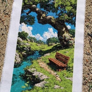 May include: A cross-stitch landscape depicts a serene scene with a stream, a bench, and a large tree. The artwork features a blue sky with fluffy white clouds, lush green foliage, and a turquoise stream. The bench is brown, and the fabric is white.