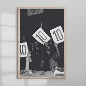 May include: Black and white framed photograph of a crowd holding up signs with the number 10. A sign that reads "Sterling Vodka" is visible at the top. The photograph is in a wooden frame.