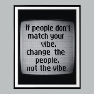 以下が含まれることがあります： 「If people don't match your vibe, change the people, not the vibe」のテキストがレトロなテレビ画面に表示された黒いフレームのプリント。テキストはピクセル化されたフォントで、グリッドの背景に設定されています。