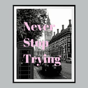 May include: Black and white framed print featuring a London street scene with Big Ben in the background. The words "Never Stop Trying" are in pink across the image. A red telephone booth is in the foreground.