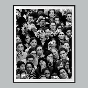 Può includere: Fotografia in bianco e nero di una folla di persone, molte delle quali tengono in mano delle macchine fotografiche. L'immagine è un primo piano, che mostra un gruppo eterogeneo di individui, tutti concentrati su qualcosa fuori dall'inquadratura. Le fotocamere sono piccole.