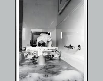 May include: Black and white photograph of a person in a bathtub, reading a newspaper. The person is wearing sunglasses and a towel on their head. The newspaper is titled "THE TIMES". The bathtub is filled with water and bubbles.